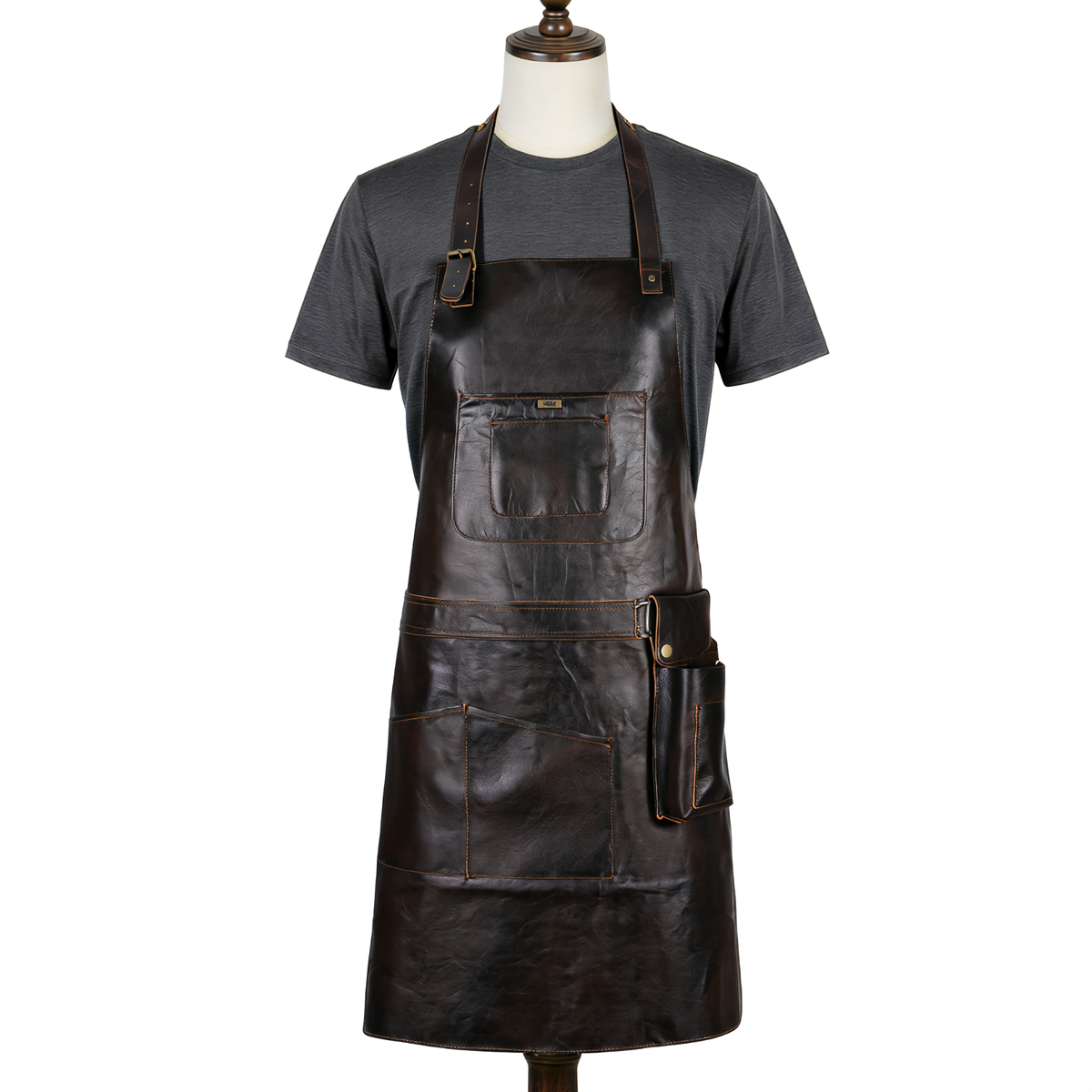 a dark brown distressed leather work apron with multiple pockets, displayed on a mannequin torso wearing a dark gray t-shirt against a plain white background.